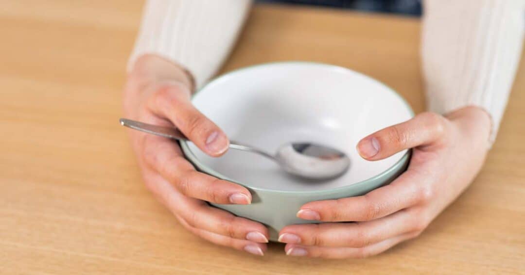 a woman holding an empty bowl with a spoon
