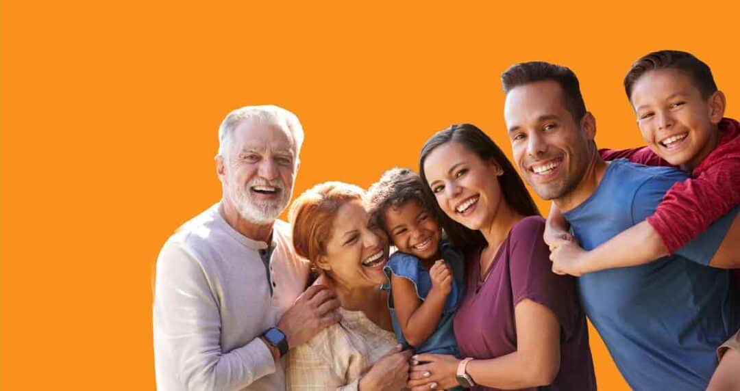 Unidos Hablemos de… Asthma & COVID-19 Conference 1 A group of six people, including three adults and three children, smile and pose together in front of an orange background. They appear joyful and are dressed casually.
