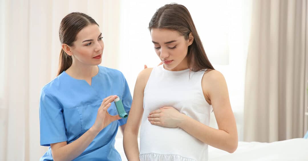 Young pregnant woman on hospital bed with doctor showing her how to use her asthma medication.