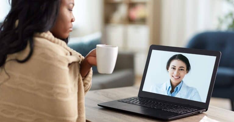a women resting at home speaking to her online asthma coach on her laptop.